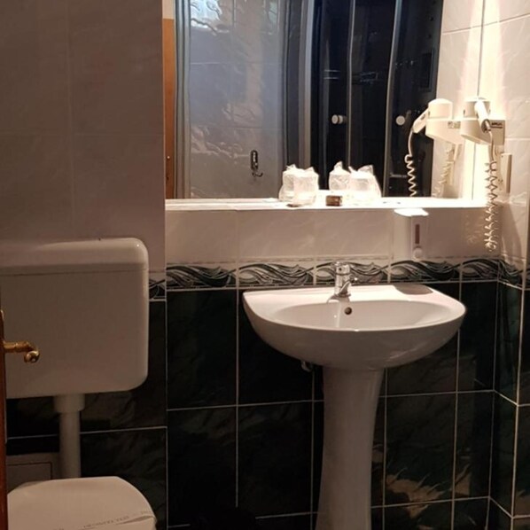 A bathroom with a white sink, a toilet, and a window with a view of the outside.