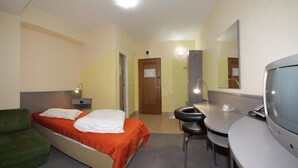 A hotel room with a bed, a desk, a chair, a TV, and a mirror. - Hotel Seneca (Baia Mare)