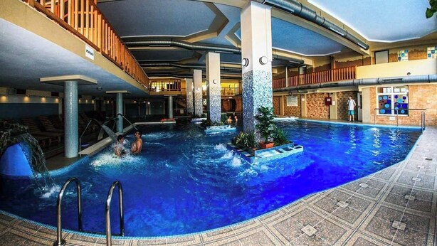 An indoor swimming pool with a wooden deck and a view of the pool area. - Hotel Seneca (Baia Mare)