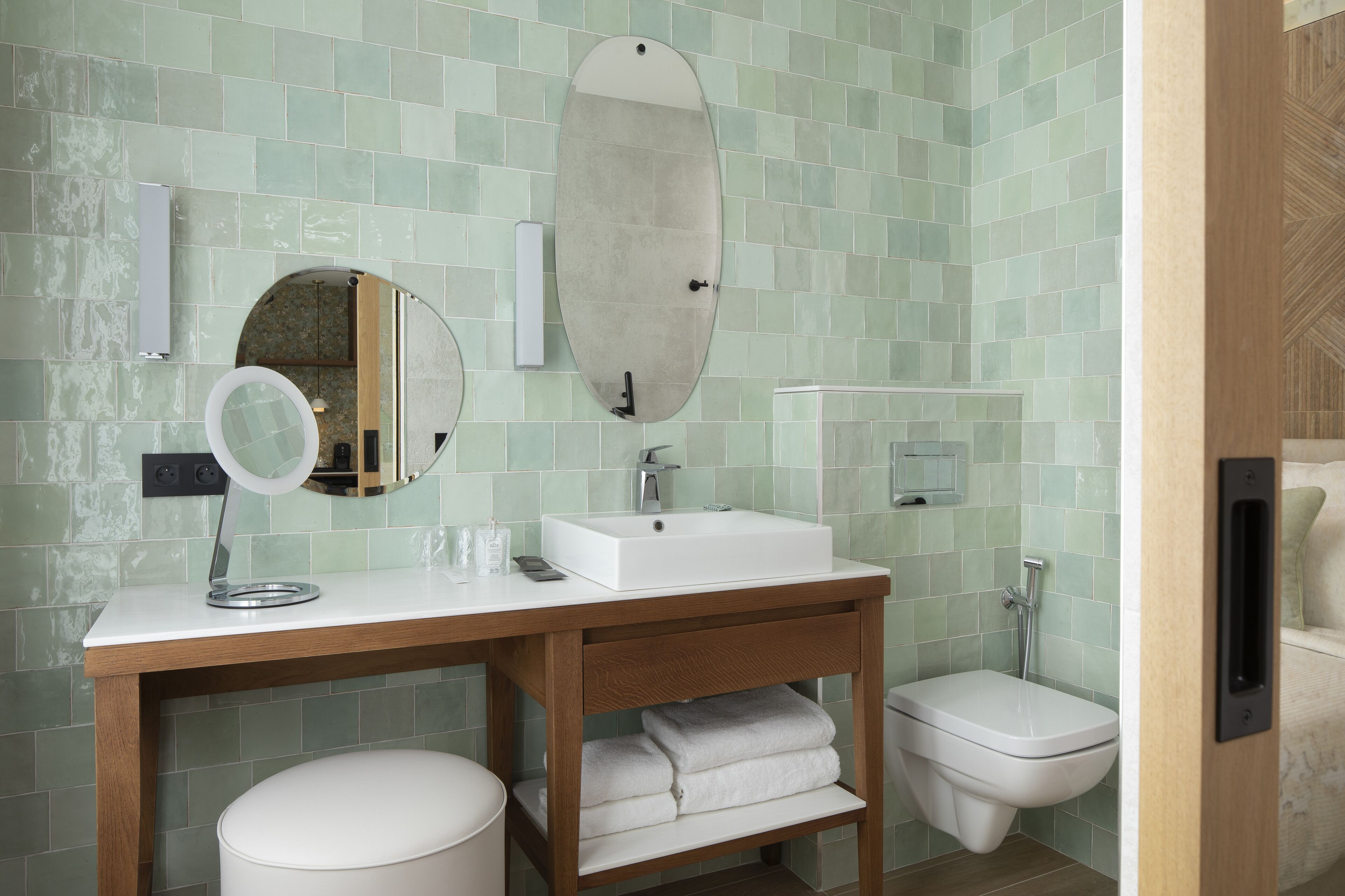 A bathroom with a wooden vanity, a white sink, a mirror, and a toilet.