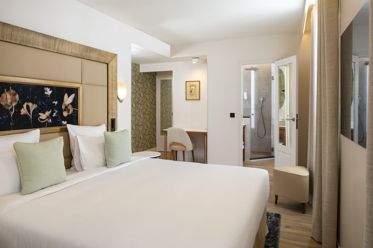 Une chambre d’hôtel avec un grand lit, un bureau, une chaise et un espace douche.