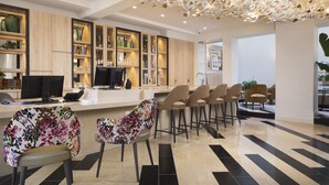 A modern bar area with a counter, bar stools, and a ceiling with a leaf-like light fixture. - Hotel Des Champs Elysees (Paris)