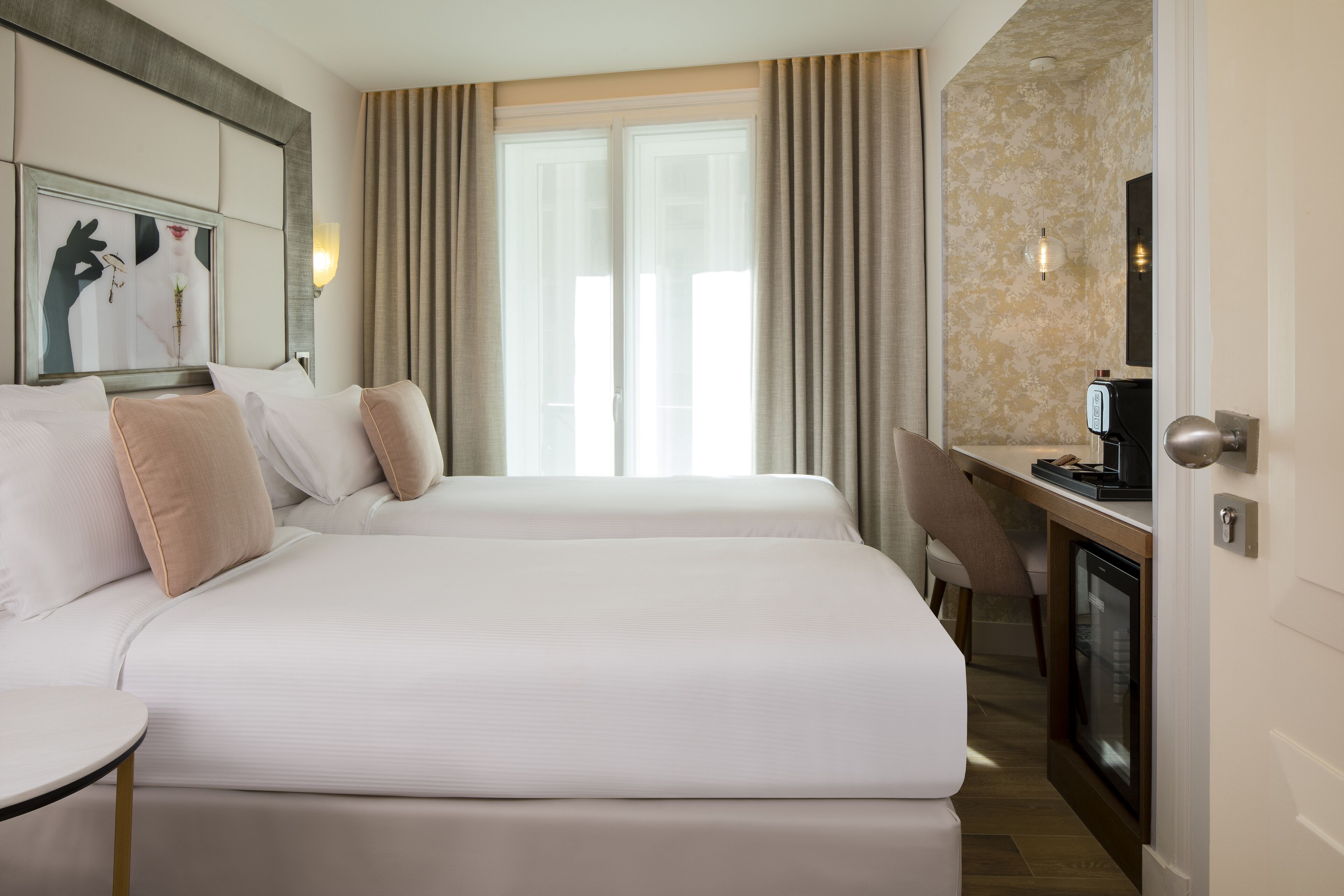 A hotel room with two beds, a desk, a chair, and a television.