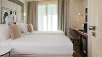 A hotel room with two beds, a desk, a chair, and a television.