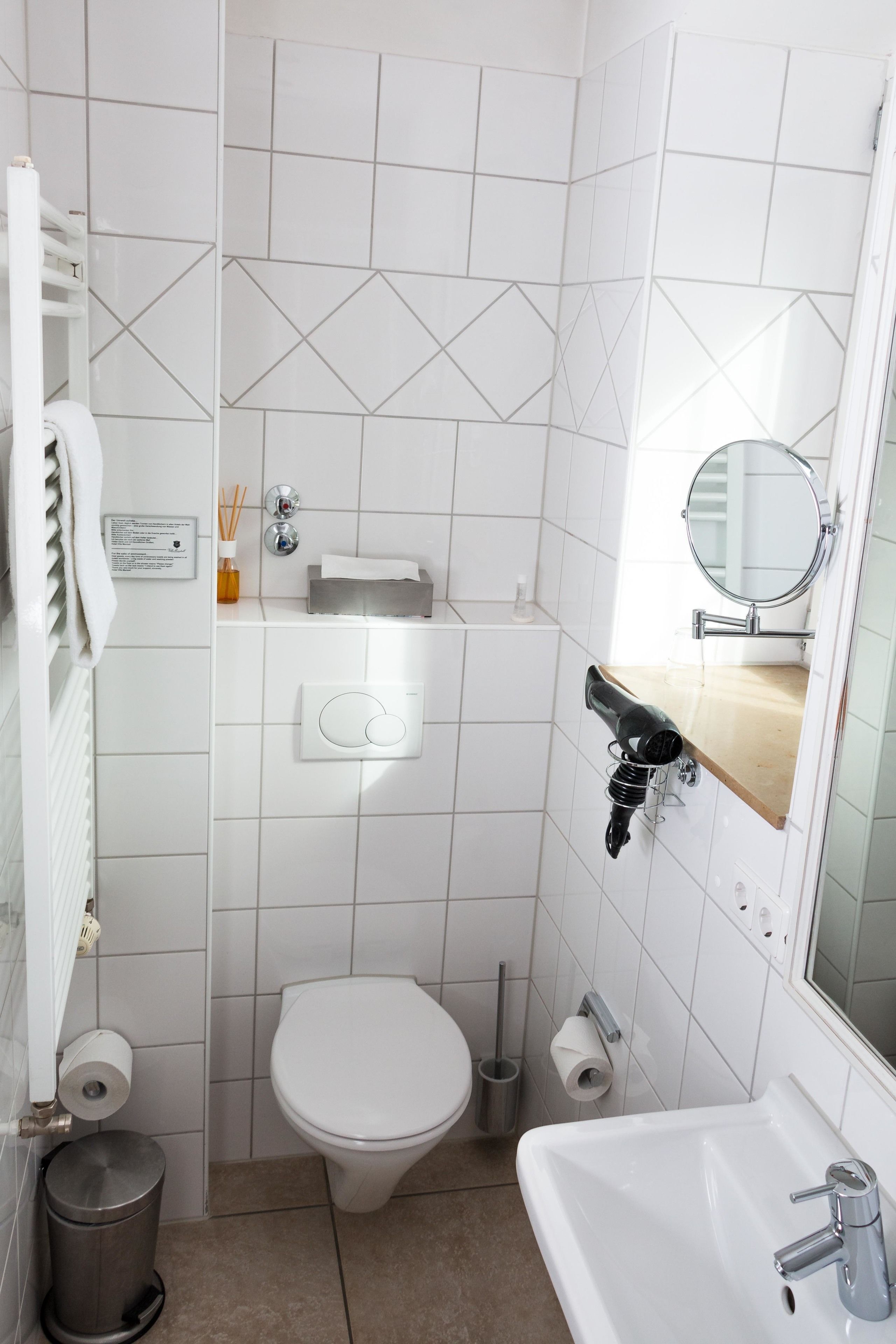 A small, modern bathroom with a toilet, sink, and mirror.