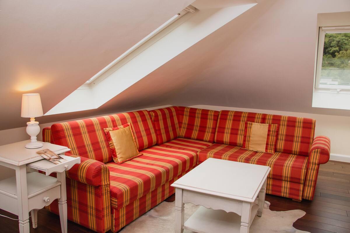 A room with a red-striped sofa, a white table, and a lamp.