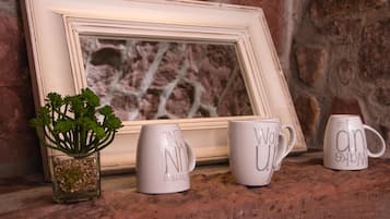 A framed picture with a plant and three mugs on a textured surface.