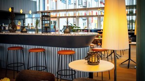 Een moderne barruimte met een centraal eiland, barkrukken en een grote lamp.