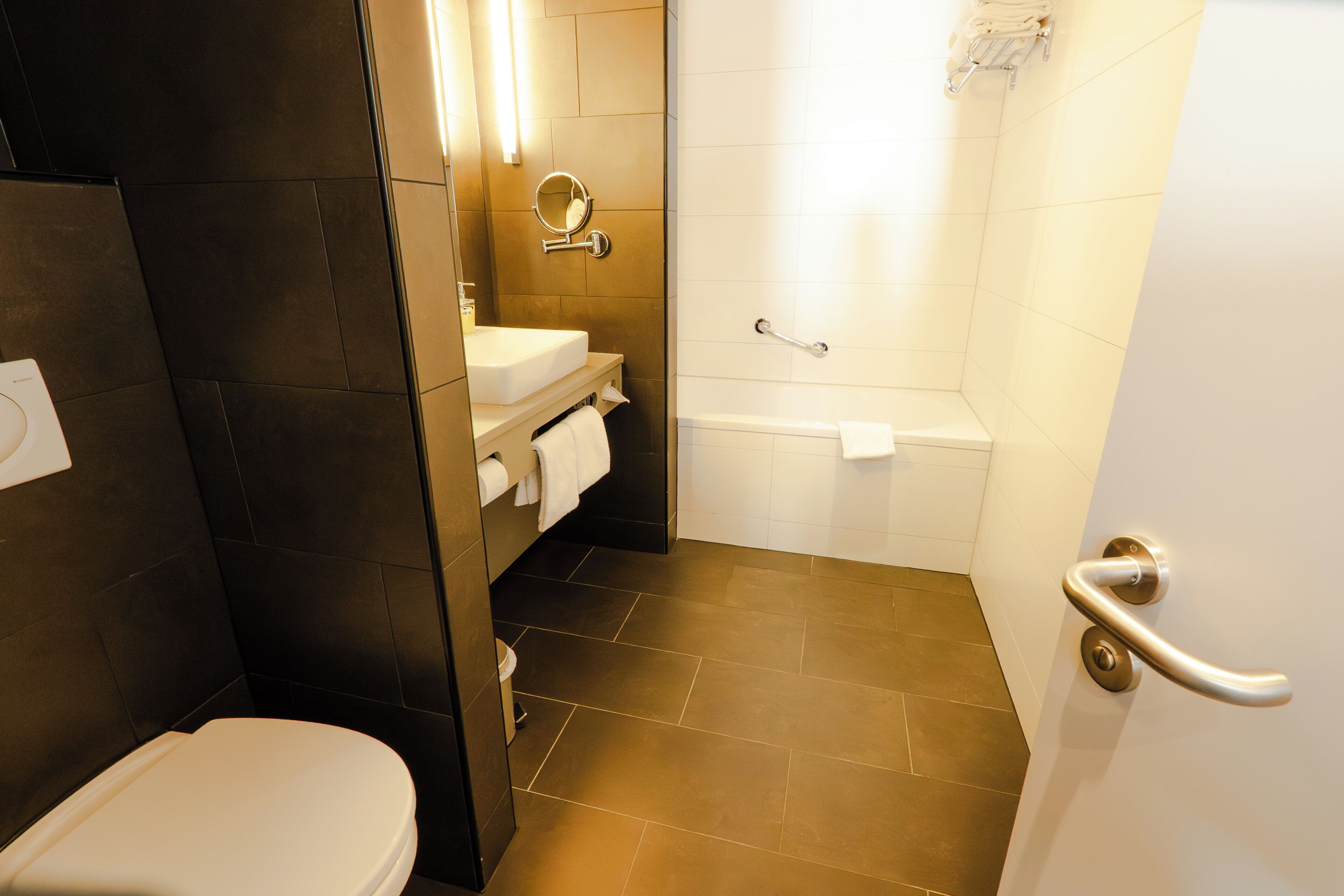 A bathroom with a toilet, sink, mirror, and shower.