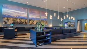 Een moderne lobby met een receptiebalie, zithoek en kunstwerken aan de muren.