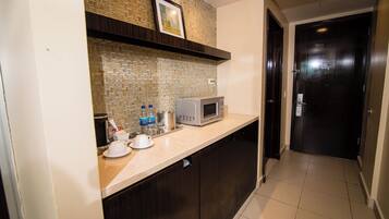 A kitchen with a microwave, coffee maker, and a framed picture on the wall.
