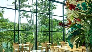 A spacious dining area with large windows offering a view of lush greenery. - Summit Rainforest Golf Resort & All Inclusive (Panama City)
