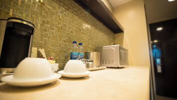 A kitchen with a tiled backsplash, a microwave, and a coffee maker.