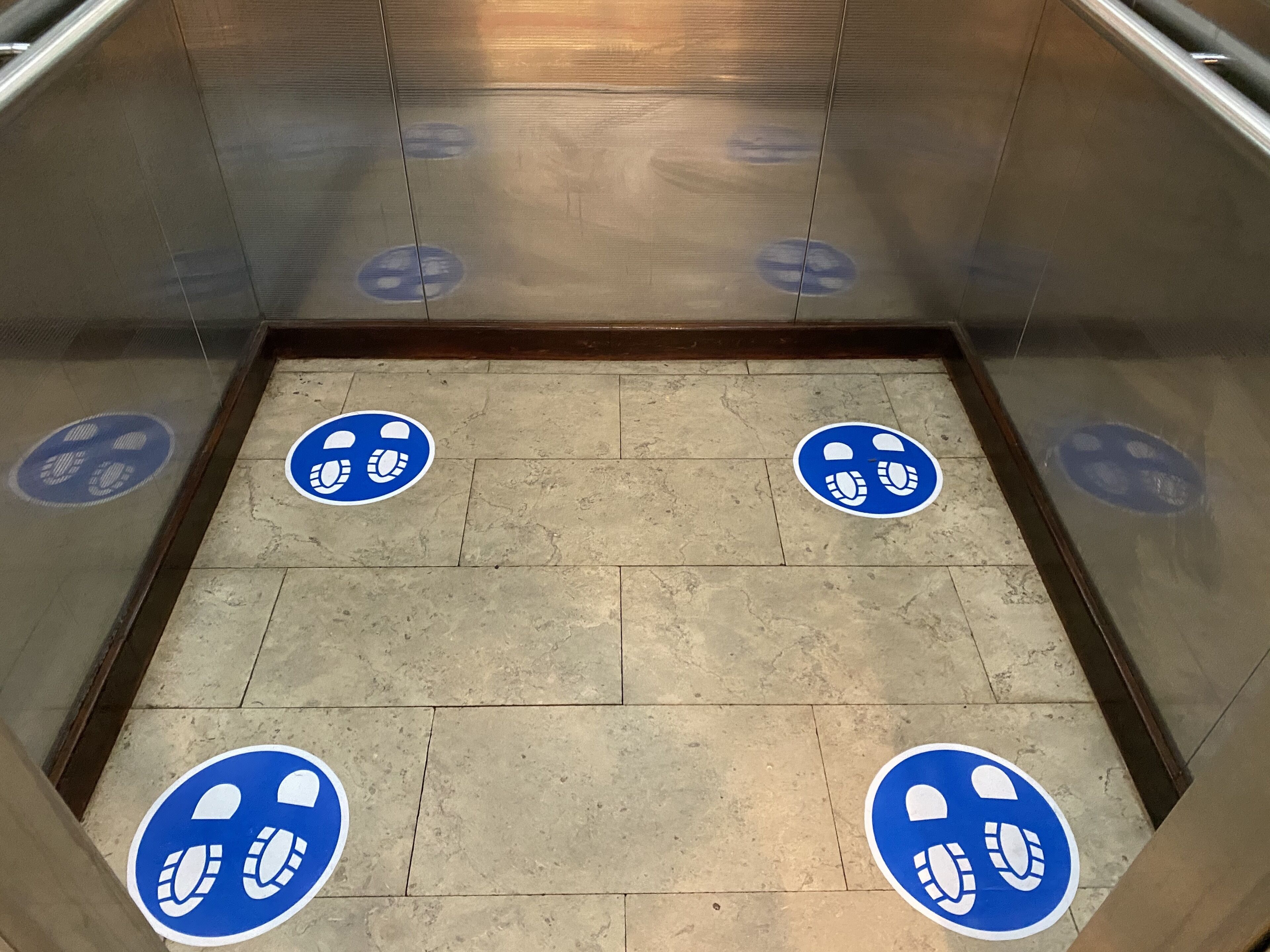 Interior de un ascensor con marcas azules en el suelo que delimitan una zona específica.