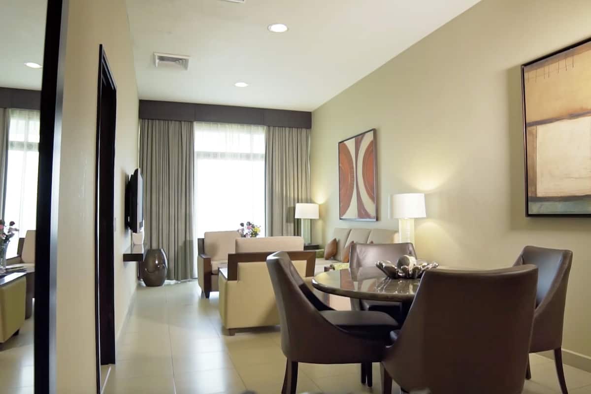 A hotel room with a dining area, a TV, and a large abstract painting on the wall.