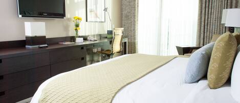 Una habitación de hotel con una cama, un escritorio con computadora, un televisor de pantalla plana, una lámpara y una ventana con cortinas.