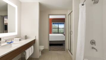 Un baño moderno con ducha, inodoro y una habitación visible con ventana.