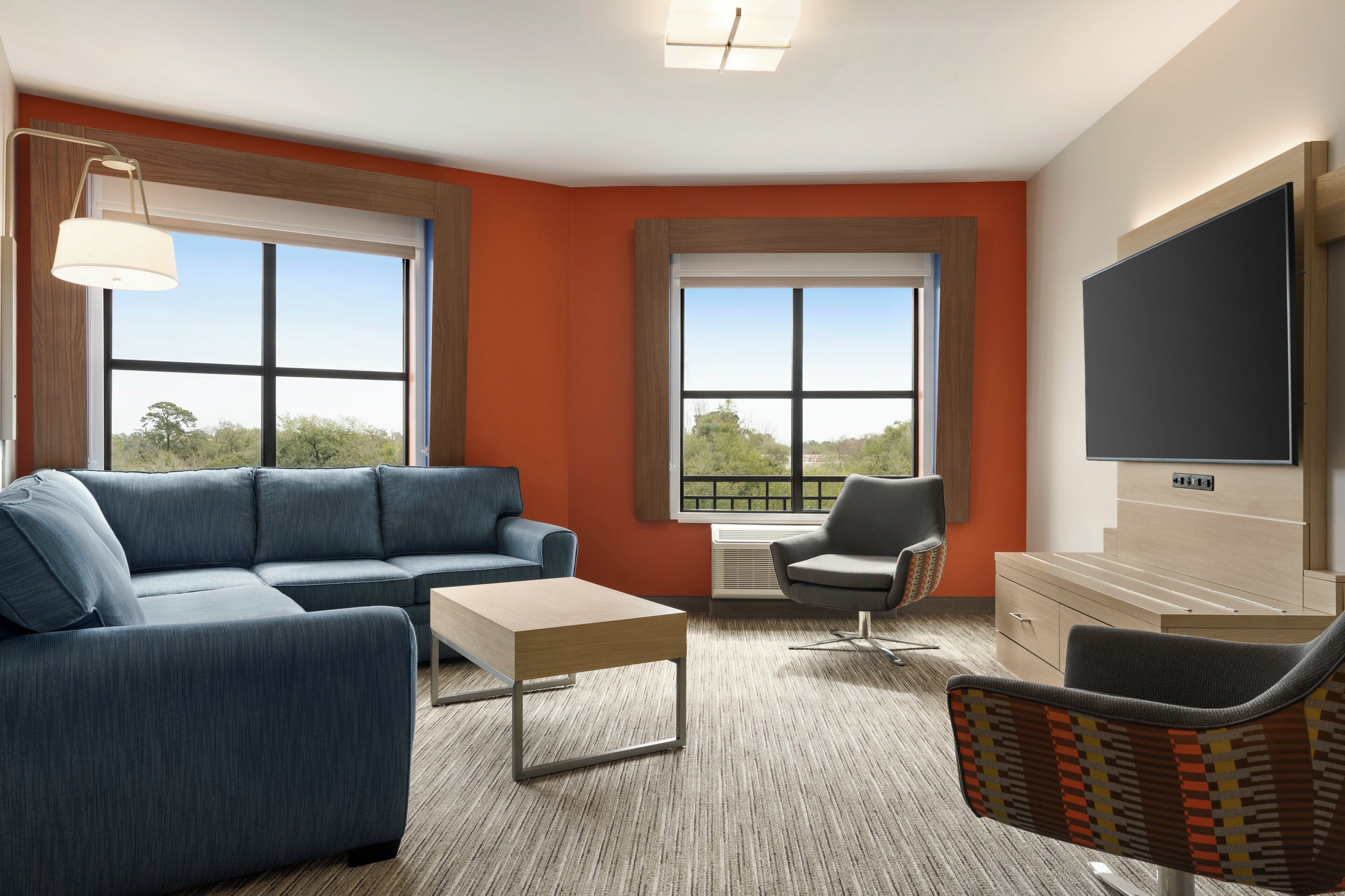 A modern living room with a sectional sofa, a coffee table, a chair, and a television.