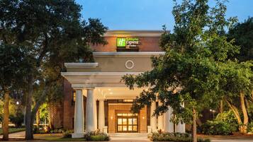 De ingang van een Holiday Inn Express & Suites hotel, met een gevel van baksteen, brede kolommen en een goed verlichte entree.