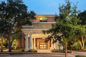 A Holiday Inn Express & Suites hotel entrance with a brick facade, large columns, and a well-lit entrance. - Holiday Inn Express & Suites Mt. Pleasant by IHG (Mount Pleasant)