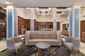 A spacious lobby with a central seating area, a kitchen in the background, and a bar area. - Holiday Inn Express & Suites Mt. Pleasant by IHG (Mount Pleasant)