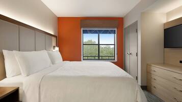 A hotel room with a bed, a dresser, a television, and a window with a view.