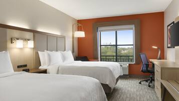 A hotel room with two beds, a desk, a chair, a TV, and a window with a view.