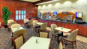 A hotel lobby with a buffet area, seating arrangements, and a large plant. - Holiday Inn Express & Suites Mt. Pleasant by IHG (Mount Pleasant)