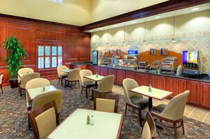 A hotel lobby with a buffet area, seating arrangements, and a large plant.