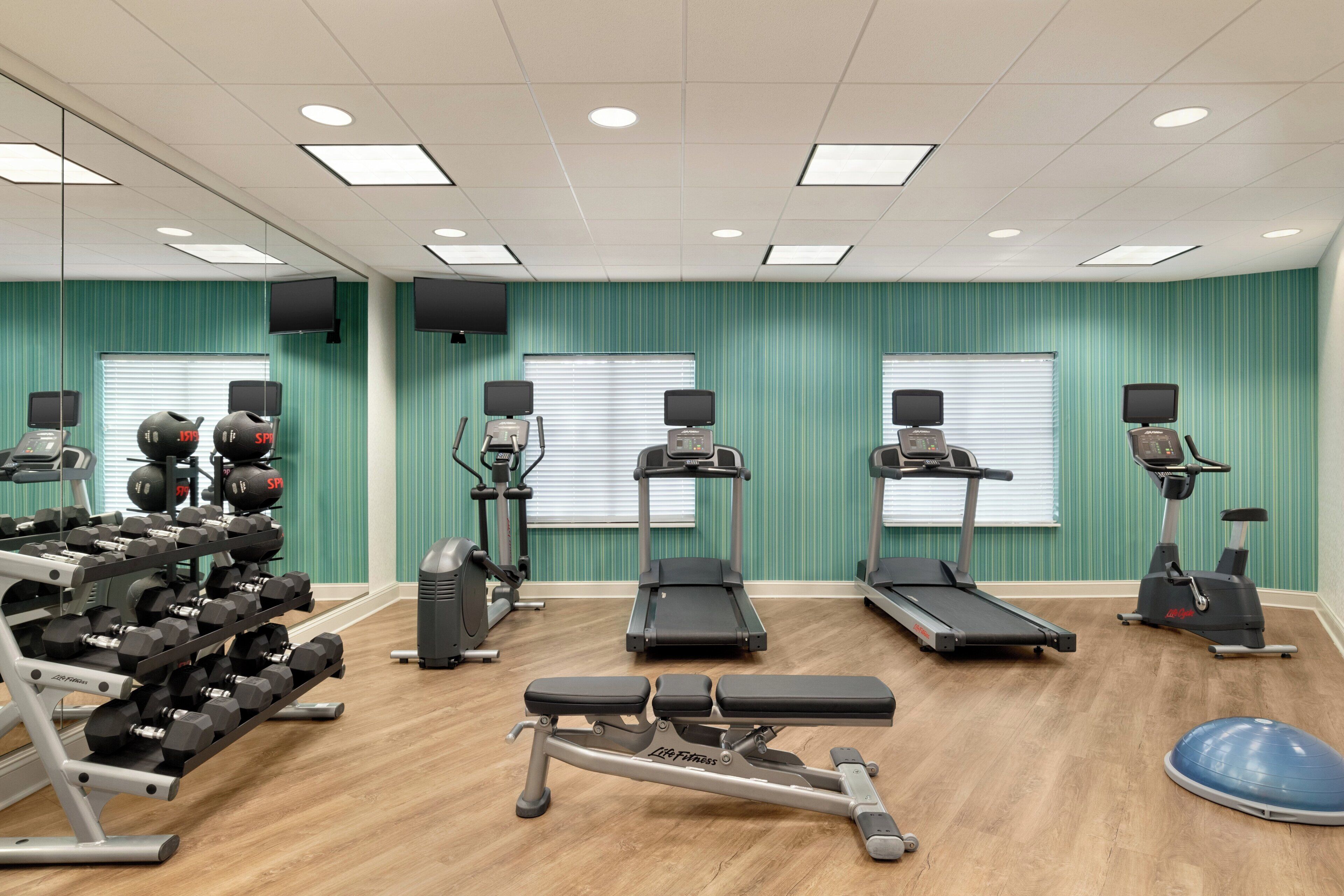 A gym with treadmills, elliptical machines, and a bench press.