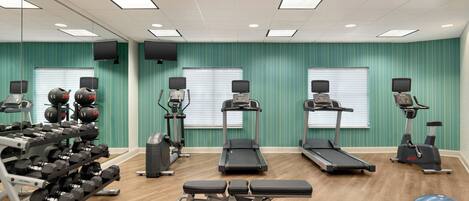 A gym with treadmills, elliptical machines, and a bench press.