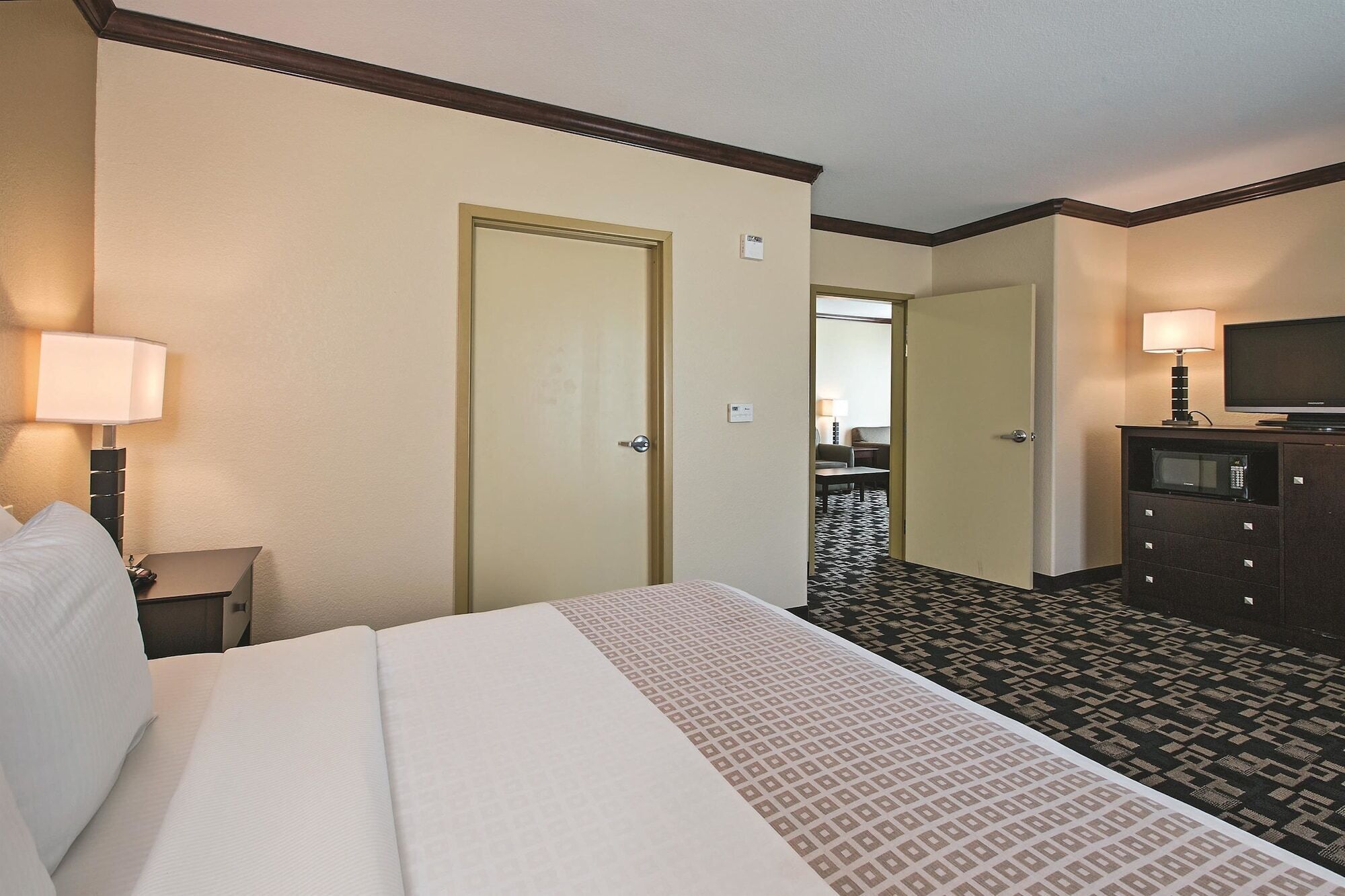 A hotel room with a bed, a desk, a television, and a dresser.