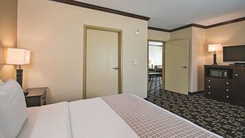 A hotel room with a bed, a desk, a television, and a dresser.