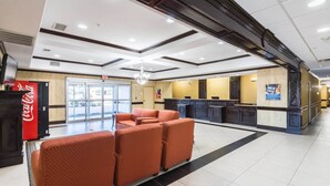 A hotel lobby with a reception desk, seating area, and a Coca-Cola refrigerator. - Motel 6 Joshua, TX (Joshua)