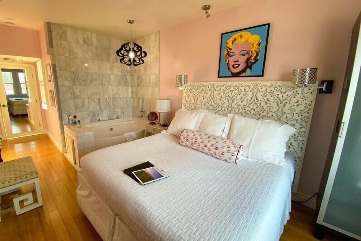 Cozy retreat with a large bed, wall-mounted light fixture, and framed artwork.