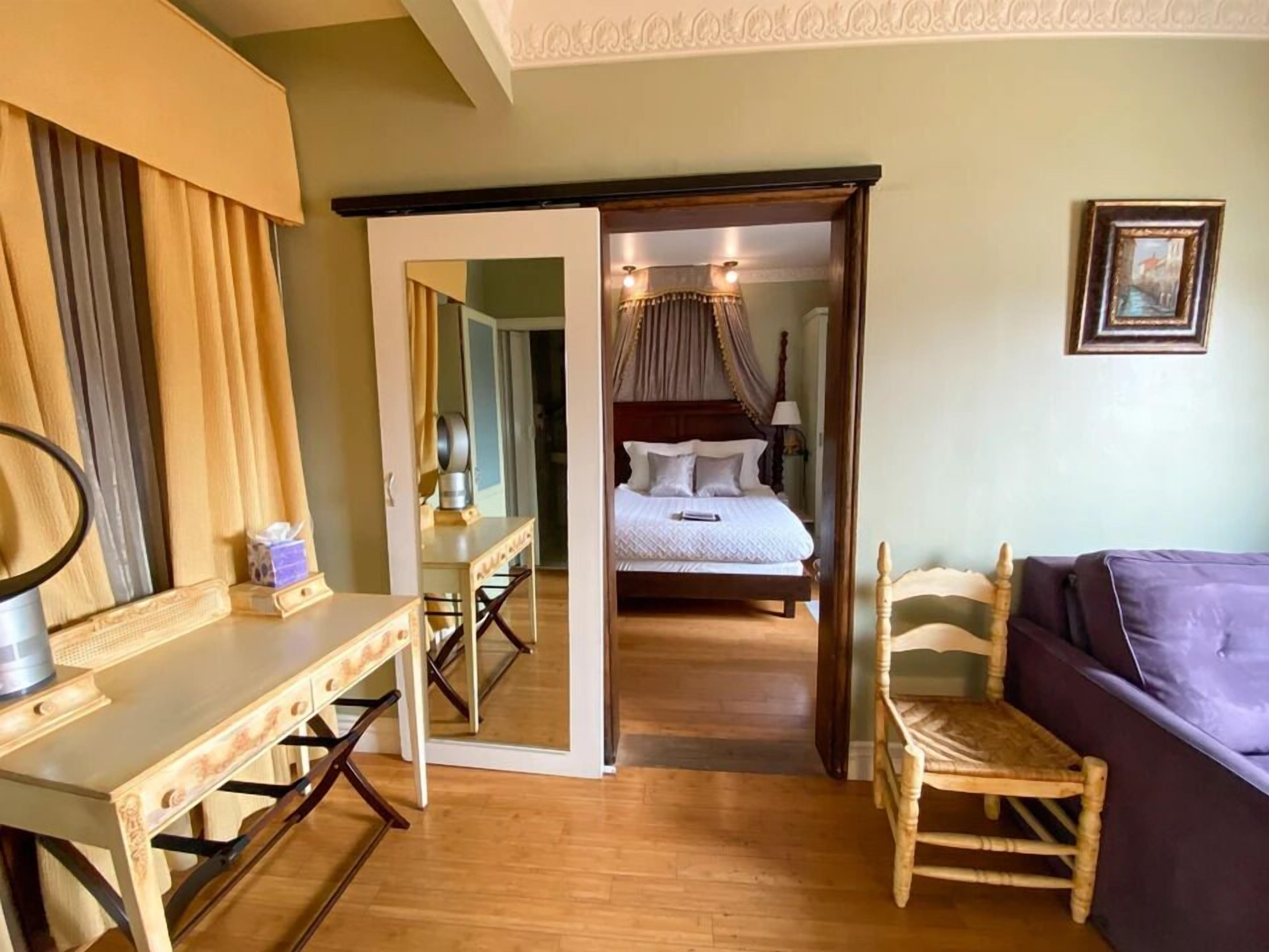A room with a bed, a desk, a chair, and a mirror.