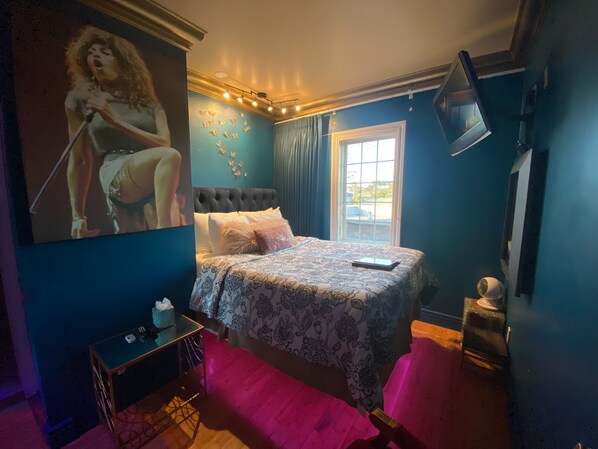A bedroom with a large bed, a desk, a chair, a window, and a wall with a butterfly mural. - Hotel 1110 - Adults Only (Monterey)