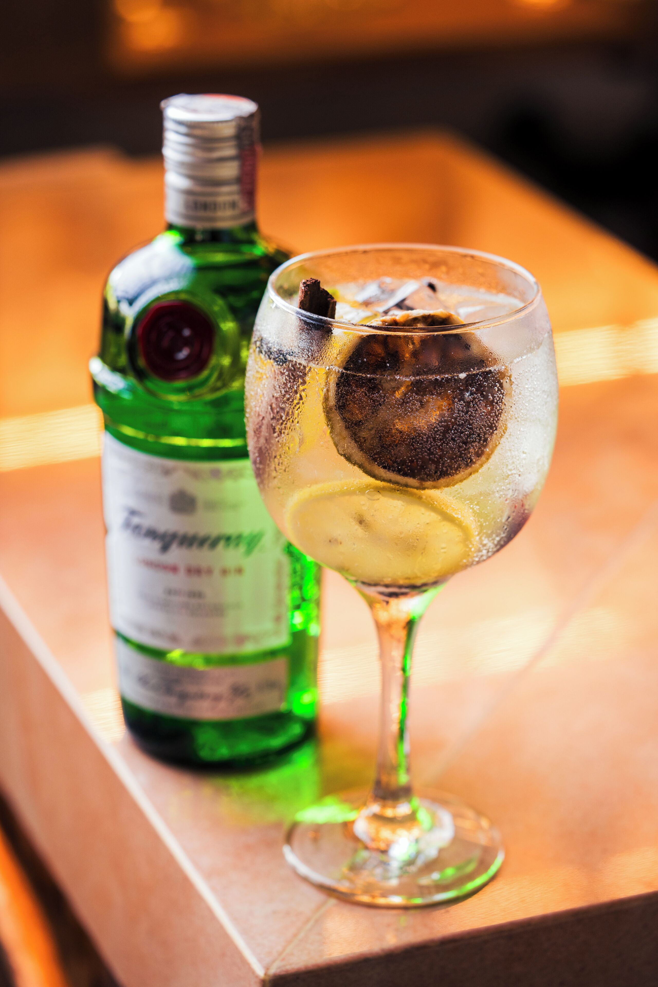 A bottle and a glass with a dark liquid and ice cubes.