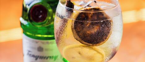 A bottle and a glass with a dark liquid and ice cubes.