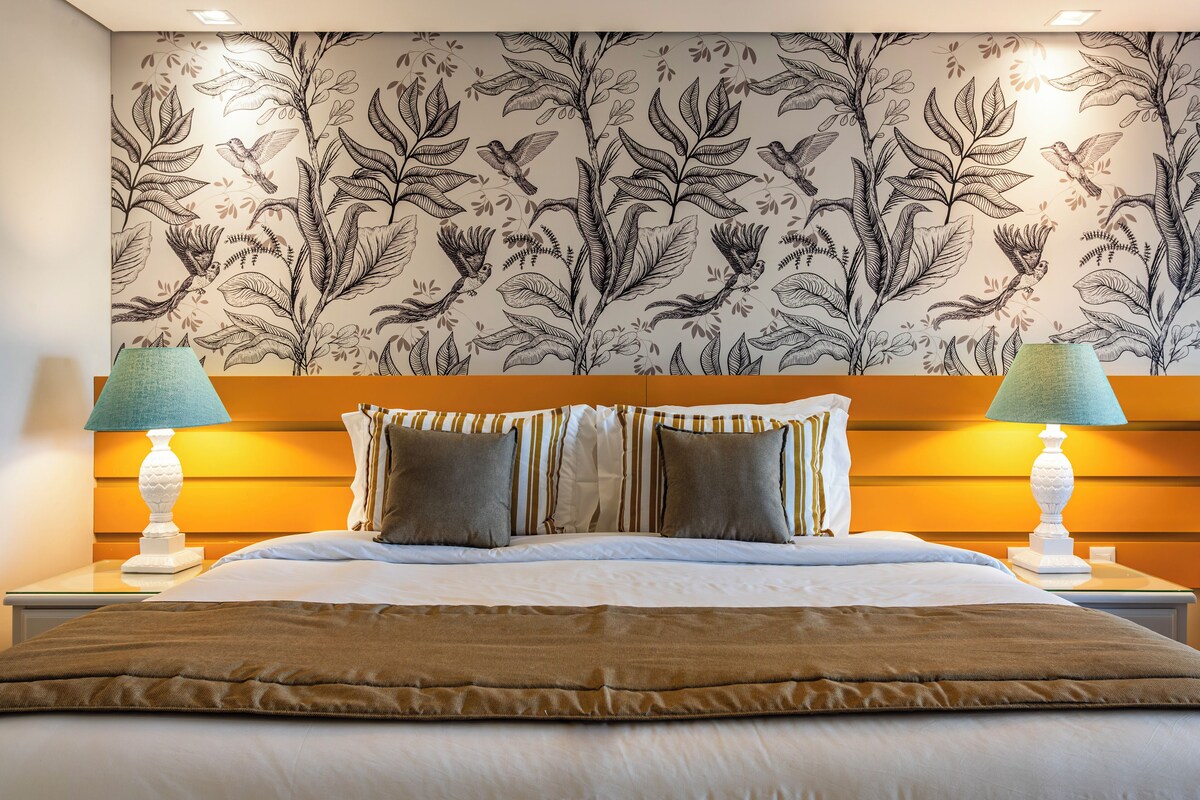 A hotel room with a large bed, two bedside lamps, and a floral wallpaper.