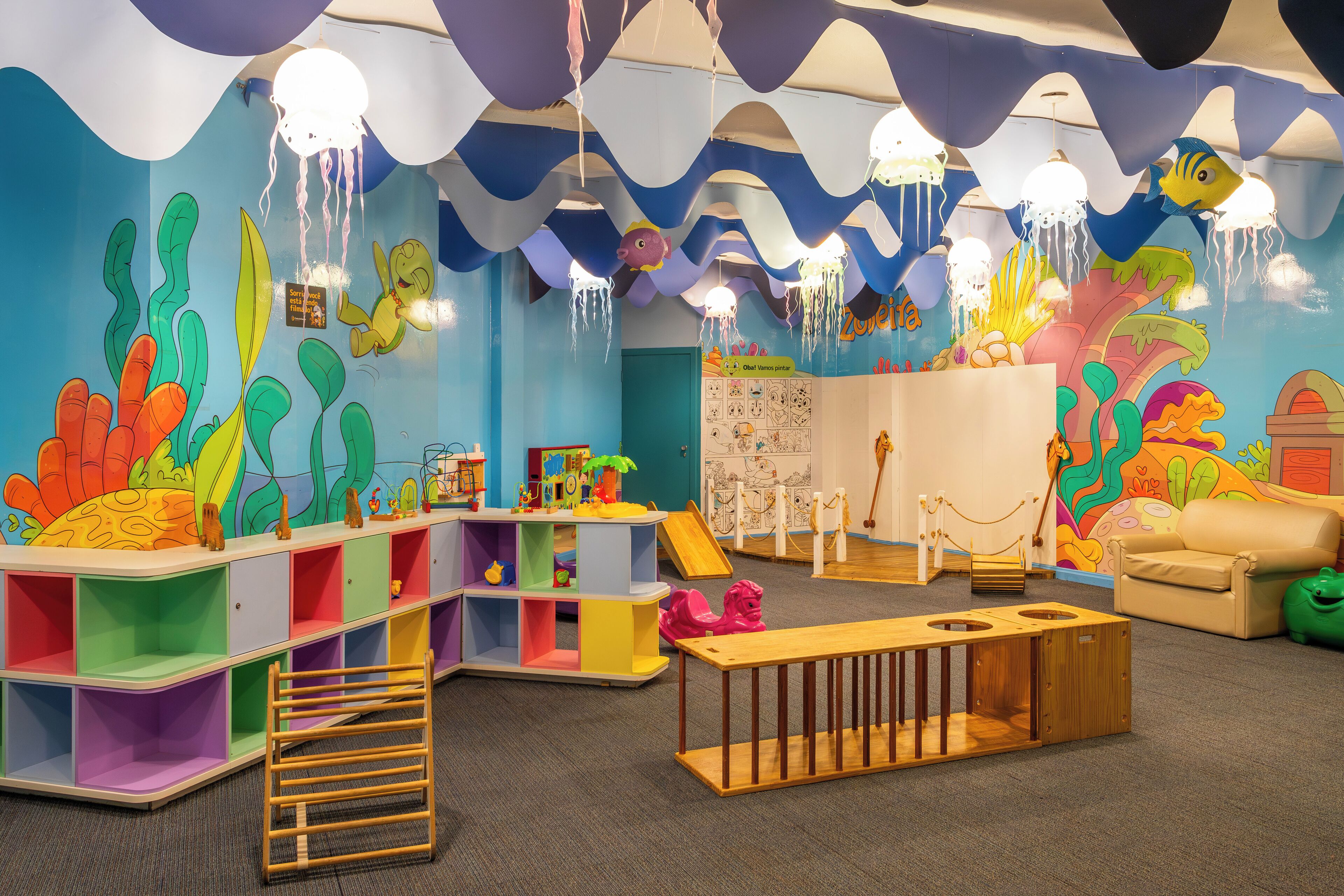 Un área de juegos infantil colorida con un tobogán, estantes y un banco de madera.