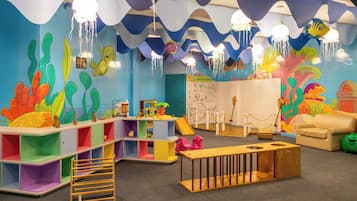 Un área de juegos infantil colorida con un tobogán, estantes y un banco de madera.