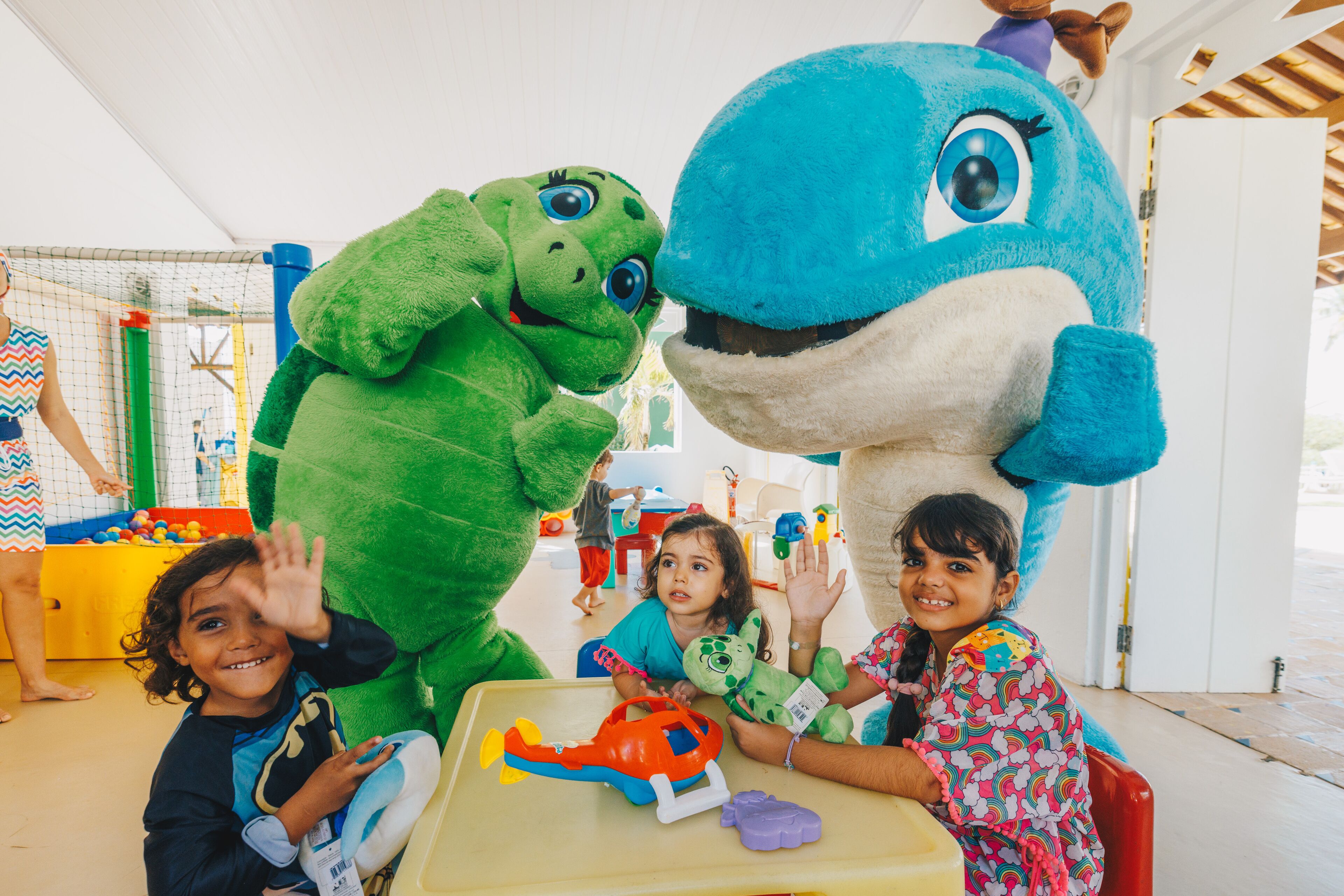 A room with a play area, including a table with toys and a large inflatable dinosaur.