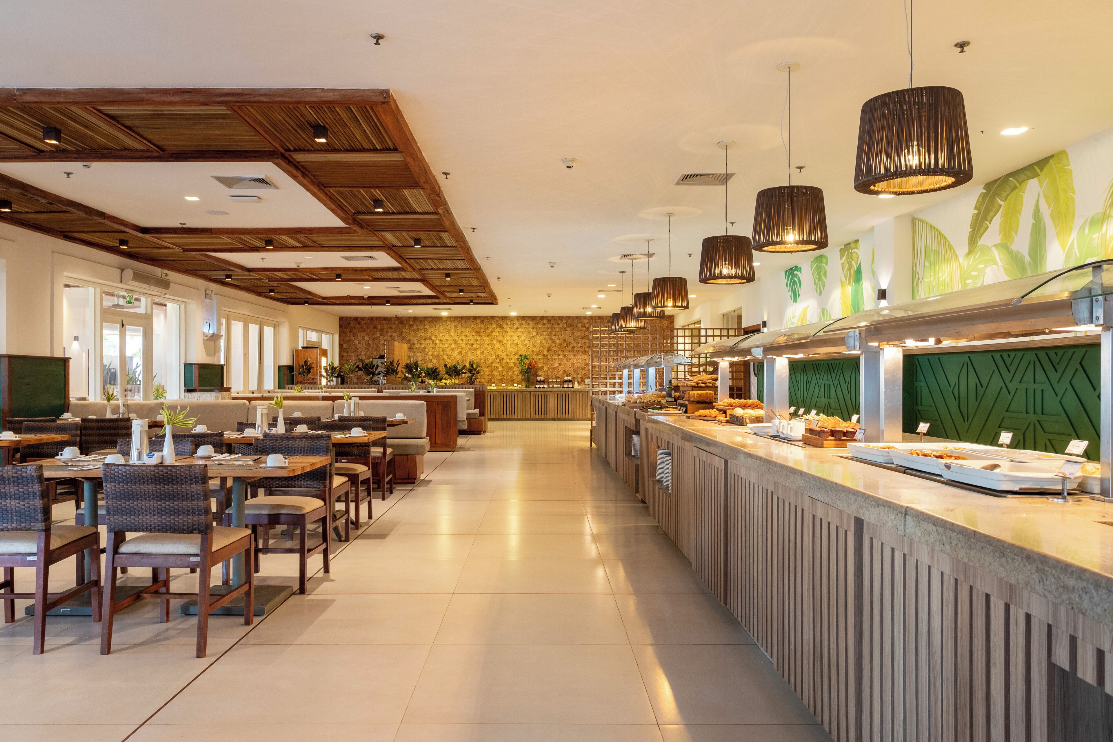 Ein modernes Restaurant mit einer langen Theke, verschiedenen Sitzbereichen und Pendelleuchten.