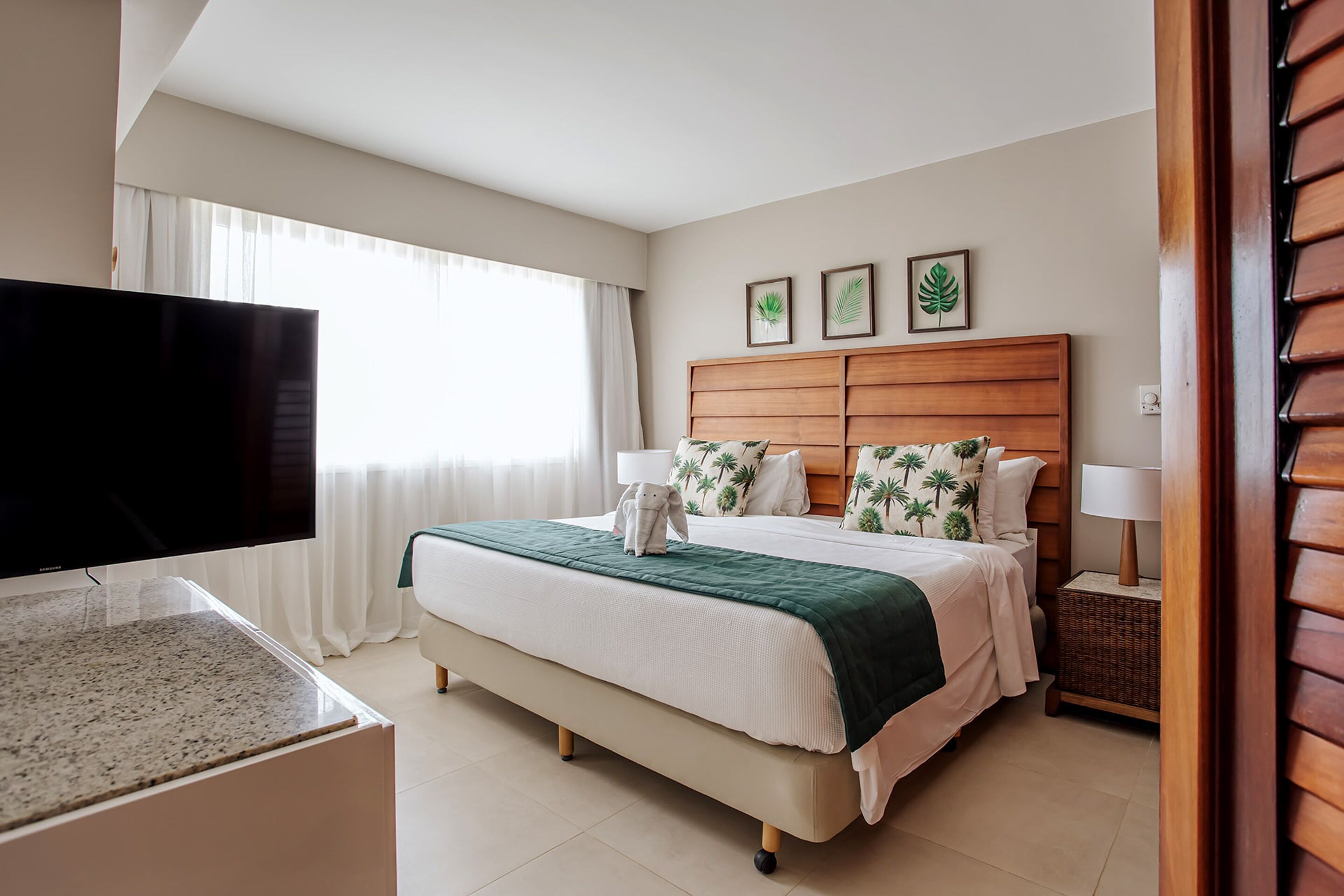 Une chambre d’hôtel avec un lit, une télévision, une table de chevet et une fenêtre avec des rideaux.