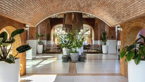 A spacious lobby with a high brick ceiling, large potted plants, and a central seating area. - Sauipe Brisa Grand Premium – All Inclusive (Mata de São João)