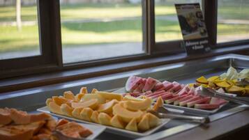 A buffet with various food items including fruits and meats.