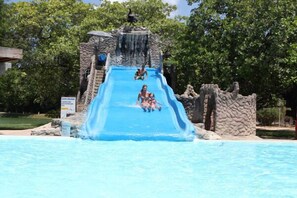 A water slide with a rocky structure at the top, leading into a pool. - Thermas Hotel Mossoró (Mossoro)