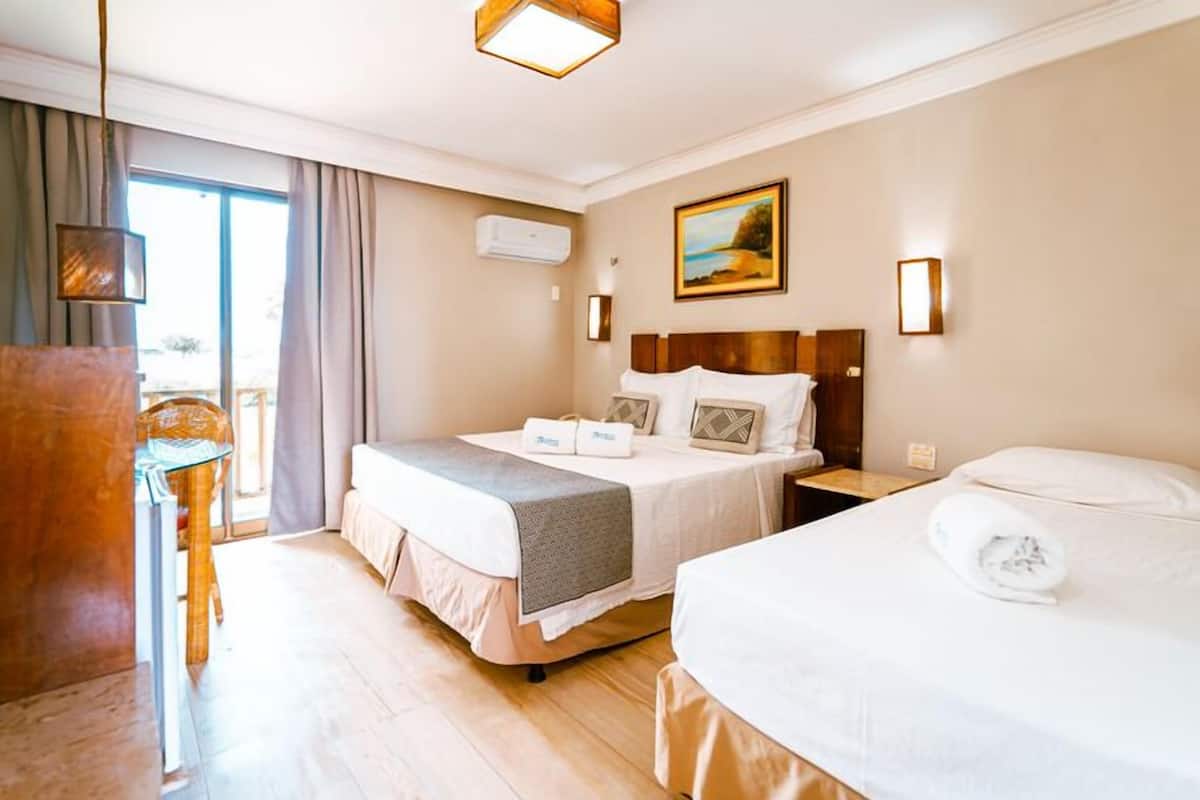 Une chambre d’hôtel avec deux lits, un bureau et une grande fenêtre.