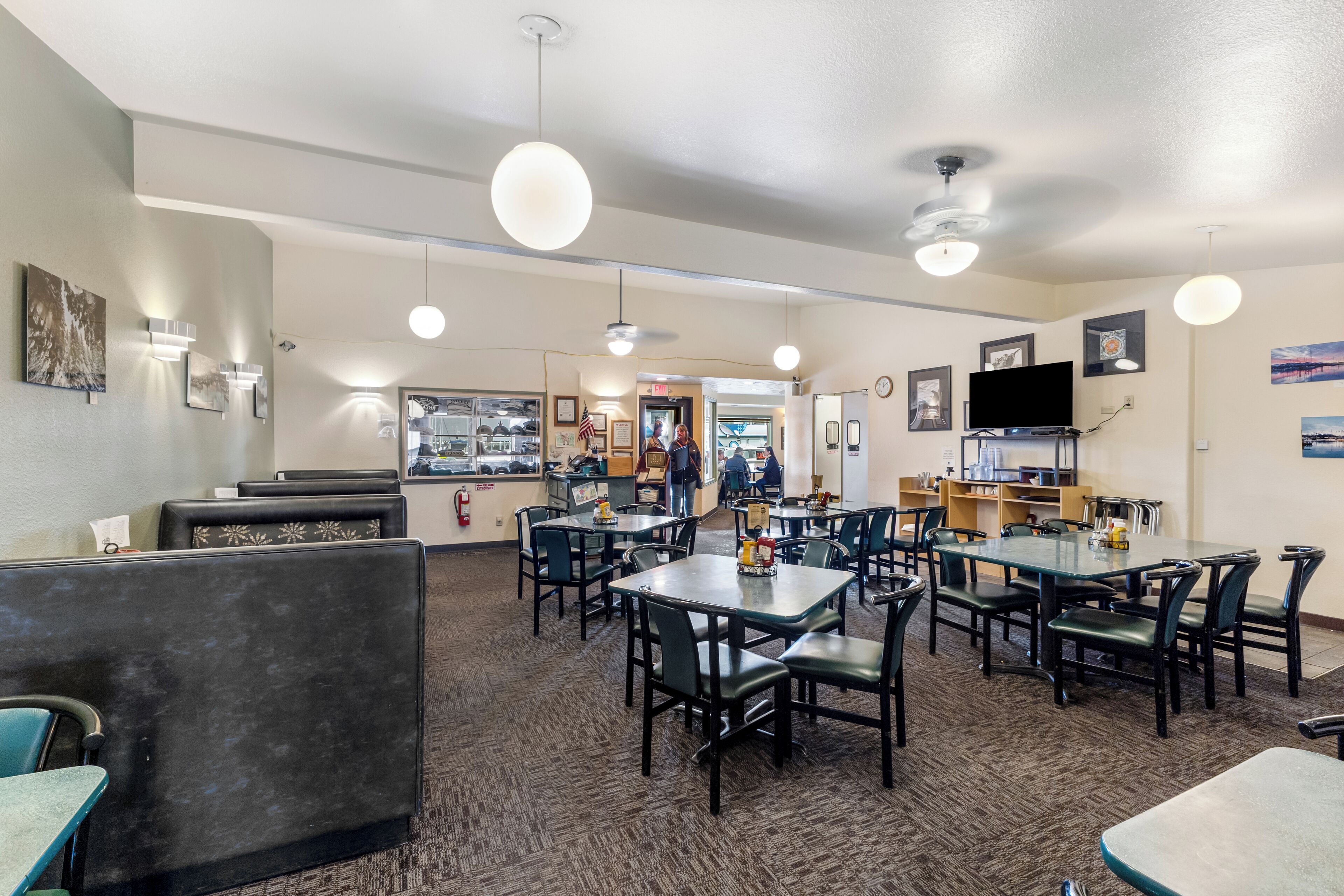 Ein Restaurant mit mehreren Tischen und Sitzgelegenheiten, Deckenventilatoren und Wandleuchten.